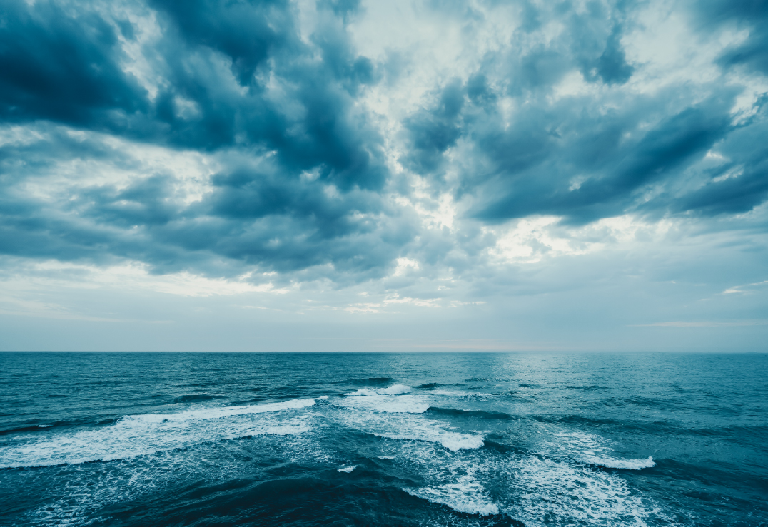 Wide view of the ocean with small waves under a cloudy, dramatic sky hints at the looming intensity of the 2025 Hurricane Season.